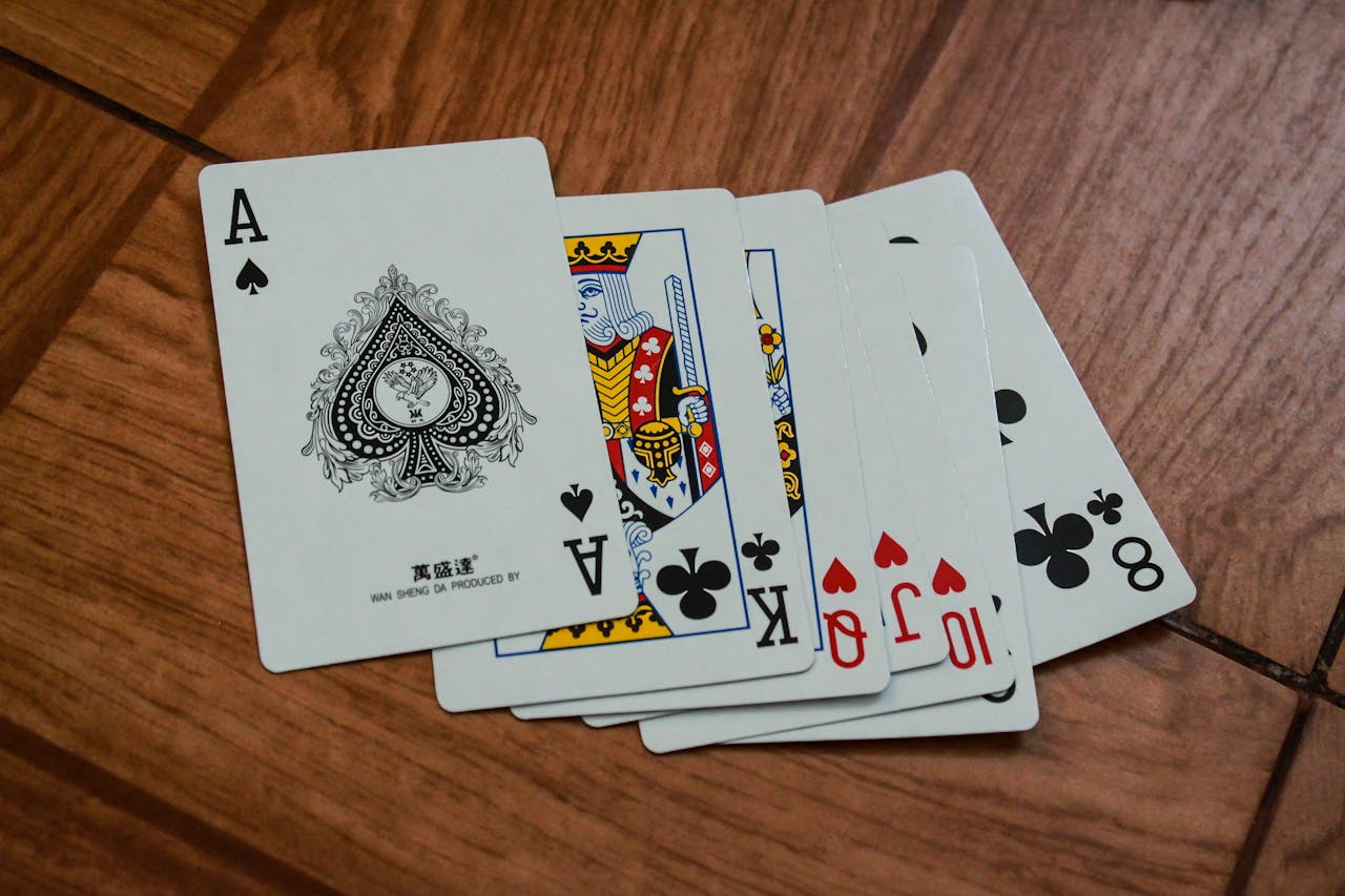 creative-01 A close-up view of playing cards on a wooden surface, featuring an ace of spades.