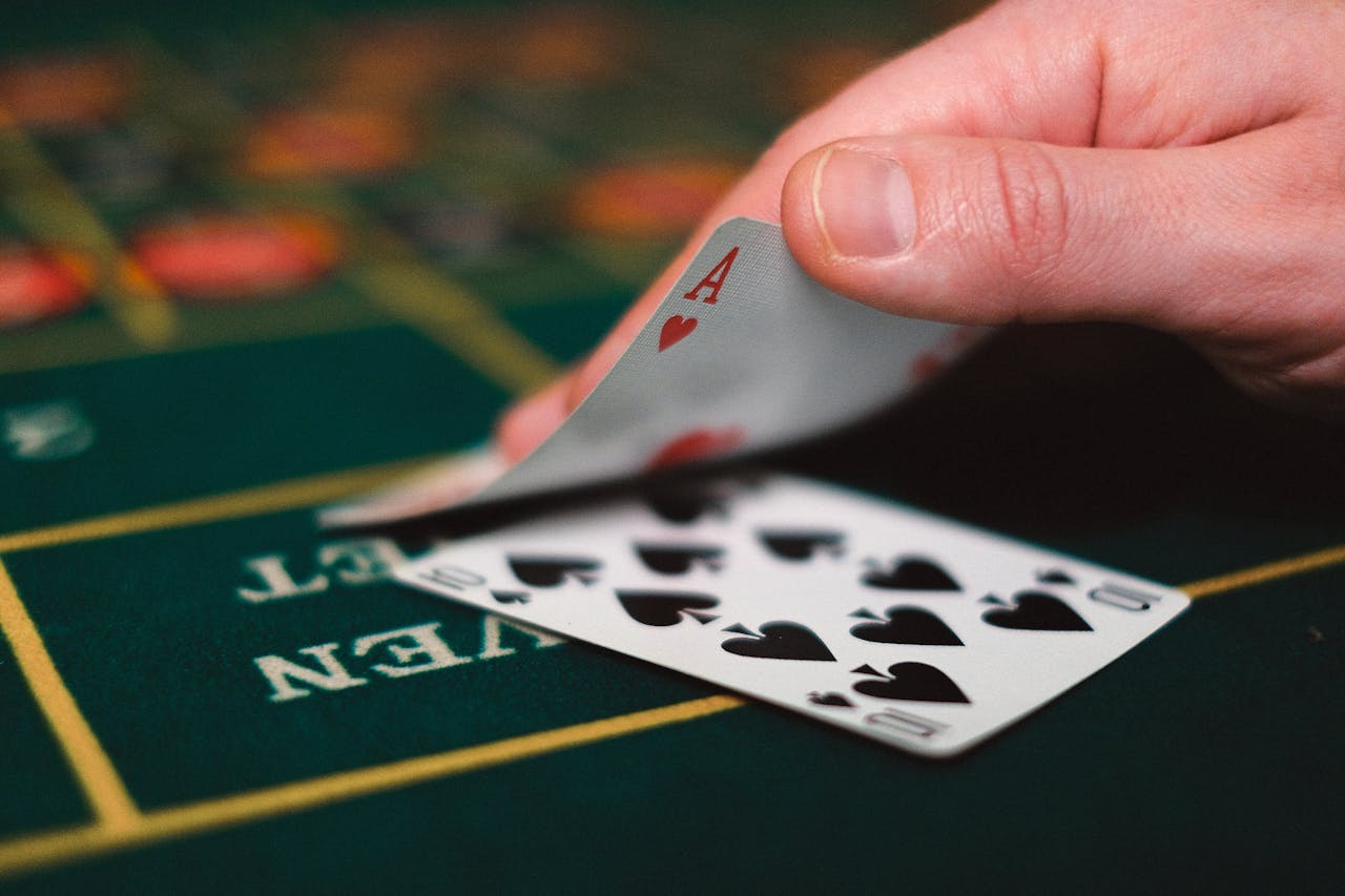 brand-01 Close view of playing cards and hand on a casino table, capturing the gambling atmosphere.