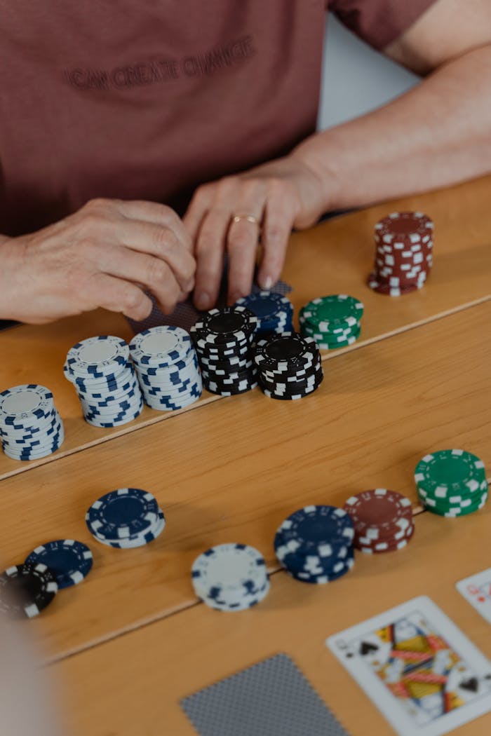 creative-03 Close-up view of poker chips and player's hands during a game indoors.