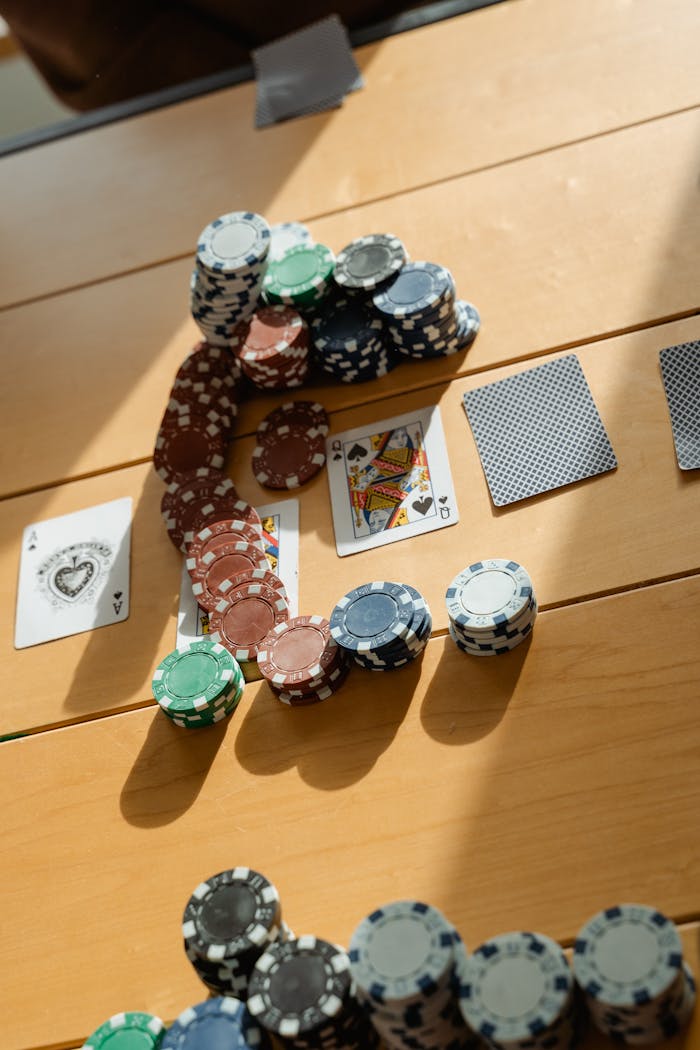 Poker game setup with chips and cards on a wooden table, in natural light.